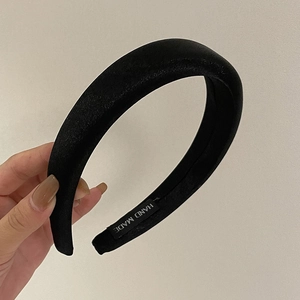 Detailed view of handmade black satin sponge headband showing the hand made inner label