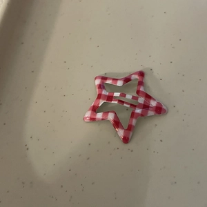 Detailed close-up of a red and white gingham star-shaped BB hair clip on a beige tray