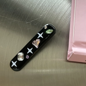 Close-up of black Y2K hair clip with colorful resin diamonds and white star patterns