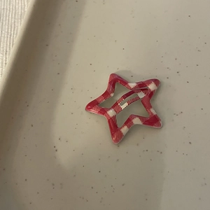 Close-up of a Y2K star-shaped hair clip with red and white checkered pattern detail