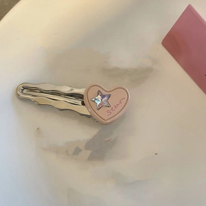 Détail d'une pince à cheveux argentée avec cœur rose et accent d'étoile colorée