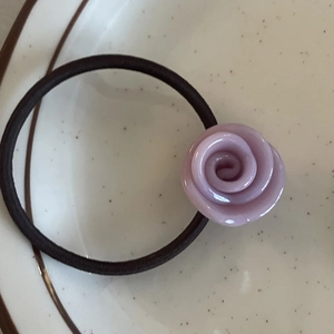 Elegant purple acetate flower hair tie with durable black elastic band in ceramic dish