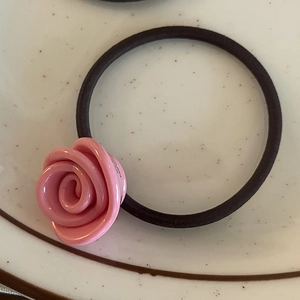 Detail view of a pink resin rose accessory on a high-elastic black hair scrunchie