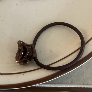 Close-up of a vintage brown acetate rose flower hair tie on a decorative ceramic plate