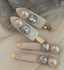 Dettaglio di eleganti fermagli per capelli dorati con perle e strass su tessuto morbido