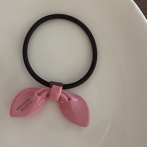 Élastique à cheveux rose oreilles de lapin en résine brillante avec ruban noir sur une assiette