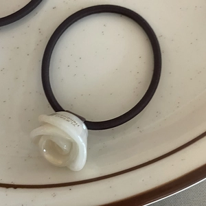 Detailed macro view of a white acetate rose on a black elastic hair tie with handmade text