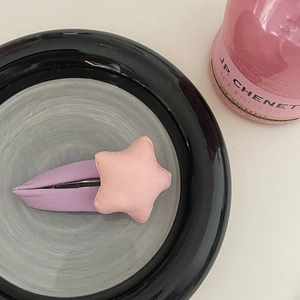 Pince à cheveux étoile rose sur base en tissu violet présentée dans un bol décoratif
