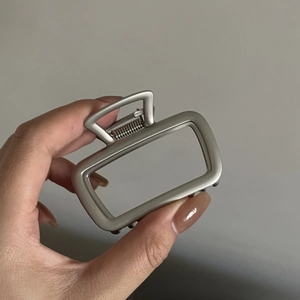 Détail d'une pince à cheveux en métal argent mat avec un design rectangulaire épuré
