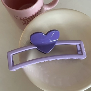 Vue macro détaillée d'une grande pince à cheveux cœur violette sur un plateau blanc