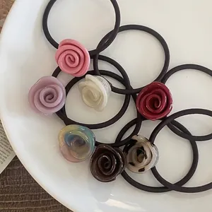 Elegant acetate rose flower hair ties in multiple colors displayed on a ceramic tray