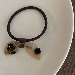 Gros plan sur élastique à cheveux nœud en acrylique écaille avec texte fait main sur assiette