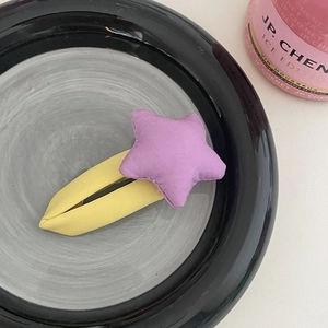 Détail d'une pince à cheveux en tissu avec étoile lavande et base jaune pastel