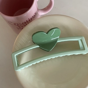 Détail d'une pince à cheveux rectangulaire de 13 cm avec motif de cœur vert sur assiette