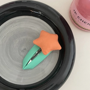 Détail d'une barrette étoile orange avec base BB clip verte pour filles et enfants