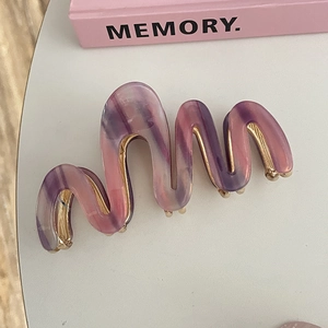 Macro view of wave shaped acetate hair claw clip with purple and pink marble texture
