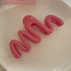 Pince à cheveux rose ondulée pour cheveux épais présentée sur un plateau en céramique