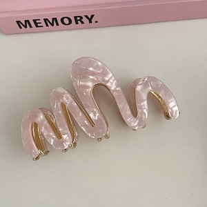 Detail of pink marble acetate hair claw with wave design and golden metal frame