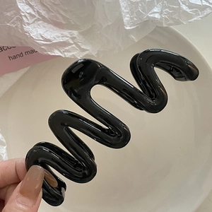 Gros plan sur une pince à cheveux noire brillante en forme de S pour cheveux épais et denses