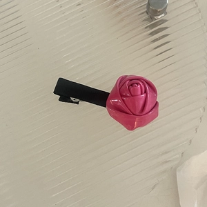 Vue détaillée d'une pince à cheveux rose en similicuir brillant sur une surface en verre