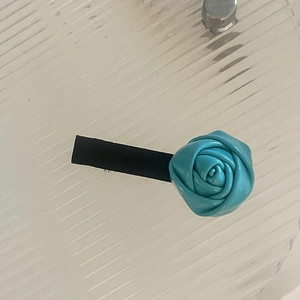Gros plan détaillé d'une pince à cheveux rose en satin bleu avec base bec de canard en ruban