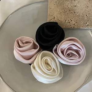 Détail de pinces à cheveux rose en satin noir, rose et blanc crème sur un plateau
