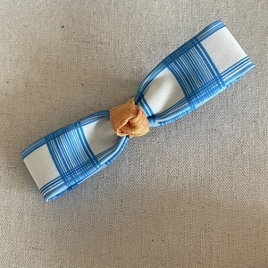 Barrette à cheveux à carreaux bleus et blancs avec nœud orange sur fond de lin