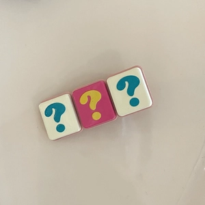 Detailed view of square hair clip charms featuring pink and white question marks