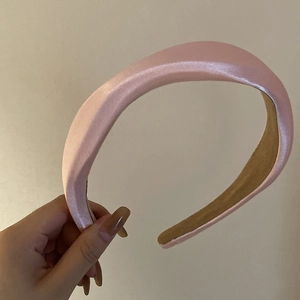 Detail of pink satin padded headband showing smooth glossy texture and non-slip lining