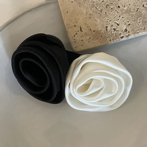 Pinces à cheveux roses en satin faites main, noir et blanc cassé sur fond de travertin