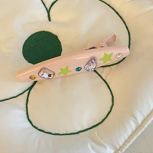 Detail shot of a pink Y2K hair clip featuring rhinestones and colorful star charms