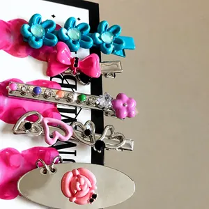 Detail of five-piece hair clip set with resin flowers, pink bows, and heart designs