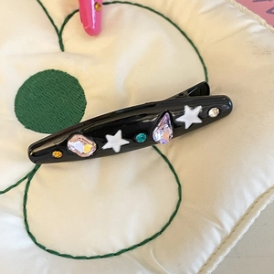Detail of black y2k hair clip with colorful rhinestones and white star accents