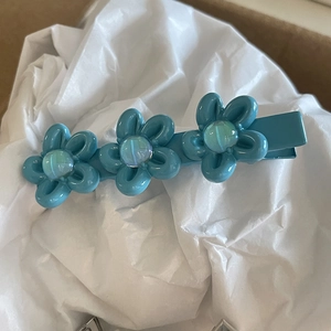 Three sky blue resin flowers hair clip with iridescent beads on a metal duckbill clip