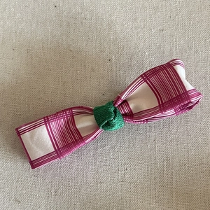 Détail de barrette à ruban à carreaux rose et blanc avec un nœud tressé vert