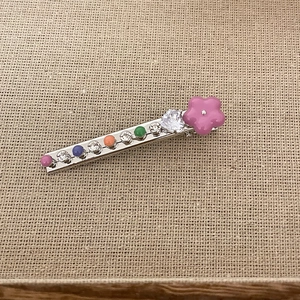 Detail of silver barrette with purple flower and colorful rhinestones on burlap