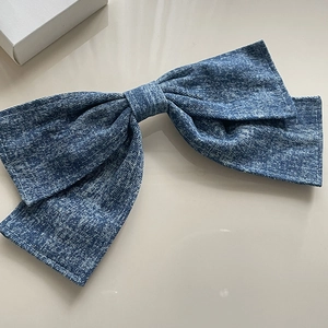 Oversized washed blue denim bow hair clip with detailed white stitching and twill texture