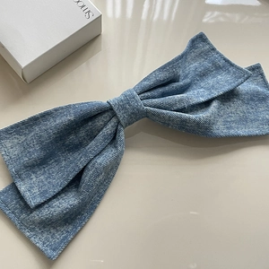 Detailed view of oversized washed denim bow hair clip with white contrast stitching