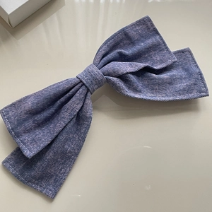 Macro detail of purple denim bow hair clip with white contrast stitching textures