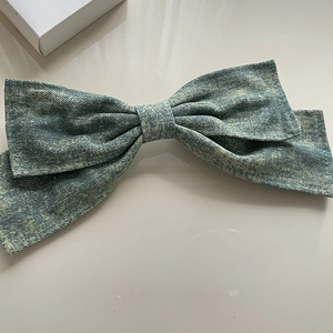 Detailed close-up of washed denim oversized bow hair clip with vintage texture