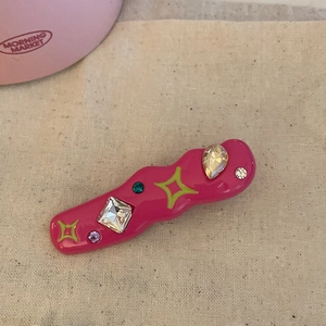 Detail of fuchsia wavy hair clip with colorful rhinestones and star prints in Y2K style