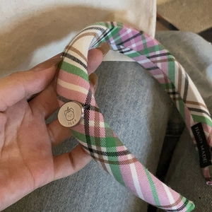 Pink and green plaid headband with metal bear charm held in hand for hair styling