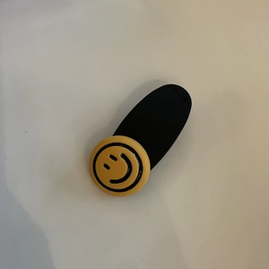 Graziosa clip per capelli con faccina gialla e base ovale nera opaca per acconciature