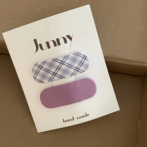 Detail of fabric wrapped oval hair clips in purple plaid and solid lilac on display card