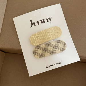 Detailed macro view of handmade yellow fabric and plaid BB hair clips on a display card