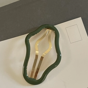 Détail d'une barrette ondulée vert foncé avec insert métallique doré brillant
