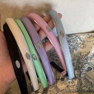 Handmade padded satin headbands in multiple vibrant colors with elegant silver metal logo