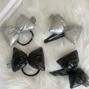 Detail of silver and black bow hair ties and clips on a soft white plush background