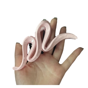 Pince à cheveux rose ondulée avec finition brillante et design en S minimaliste dans la main