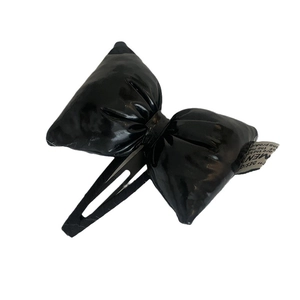 Minimalist black shiny faux leather bow hair clip with decorative woven label for women